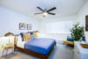 Bedroom with large bed and window ceiling fan and modern bedside tables.