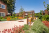 four wooden benches a landscaped path with greenery flowers and trees