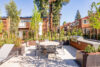 Outdoor patio with BBQ and dinning table, Surrounded by tall evergreen trees in a peaceful setting, 2 story apartment building with cedar siding, mature evergreen trees