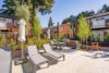 Outdoor patio with BBQ and dinning table, Surrounded by tall evergreen trees in a peaceful setting, 2 story apartment building with cedar siding, mature evergreen trees