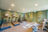 Gym facility, three treadmills and two elliptical machines, mint green walls and natural light from windows