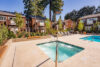 Spa hot tub at apartment complex, two-story buildings with cedar siding, balconies overlooking pool area, landscaping, communal recreational space